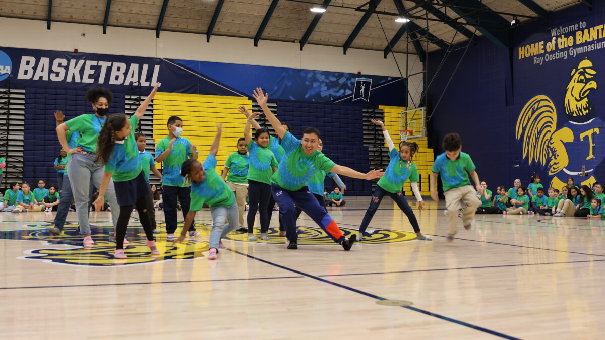 Elementary students perform class dance in green and blue tie-dye shirts